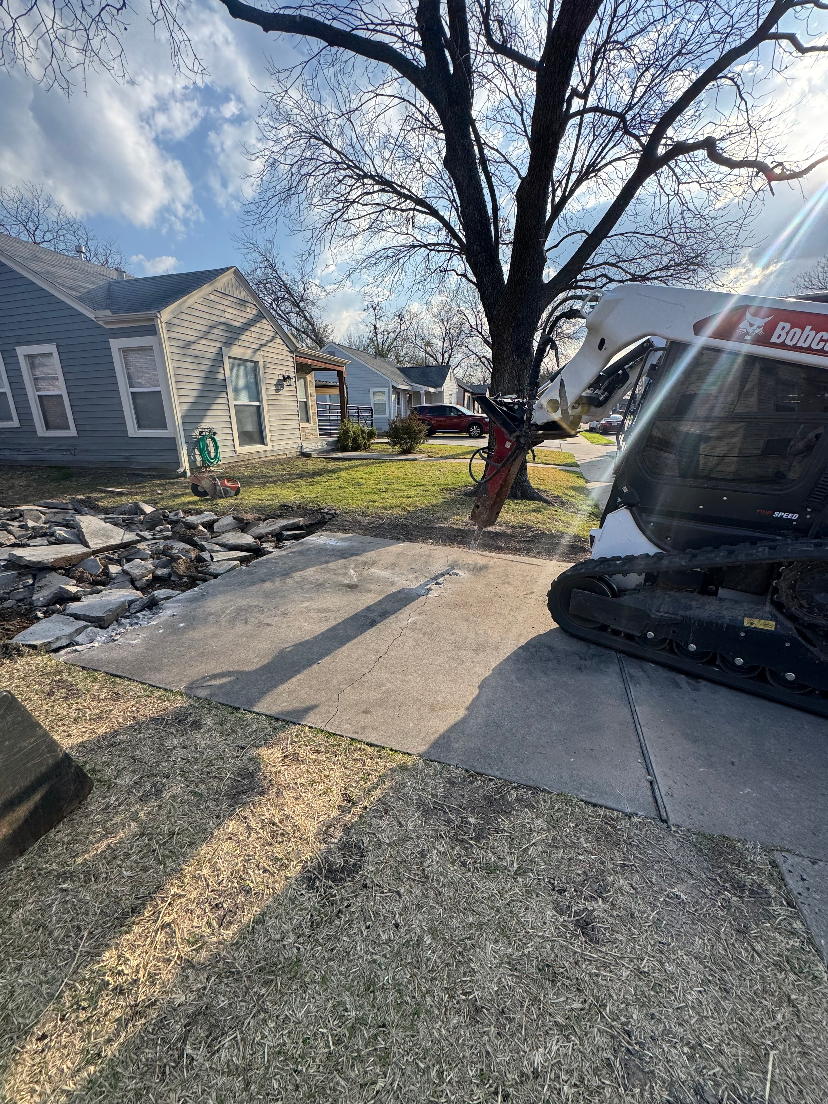 Bobcat breaking up old concrete driveway for replacement