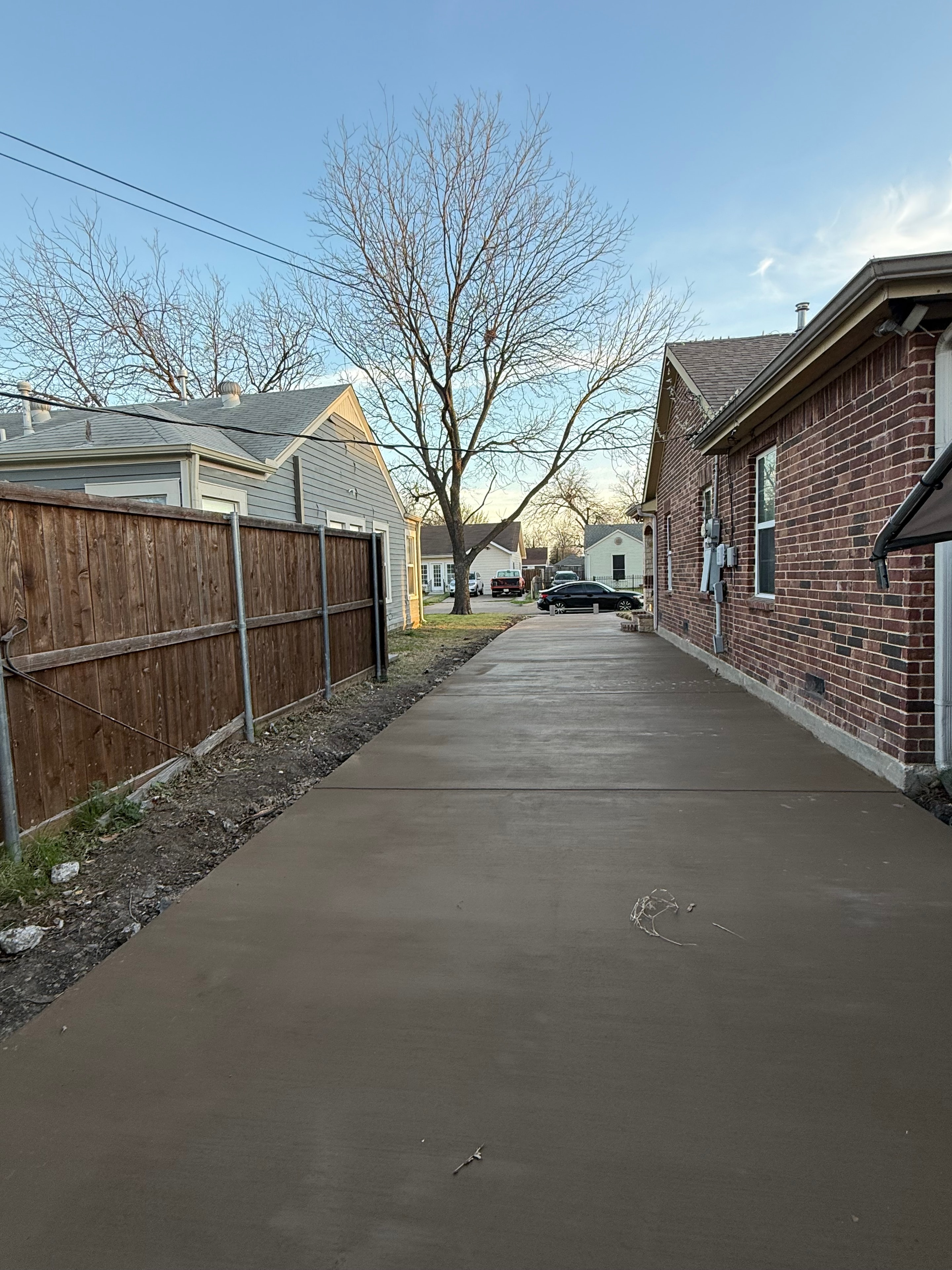 Fresh concrete driveway pour next to brick home