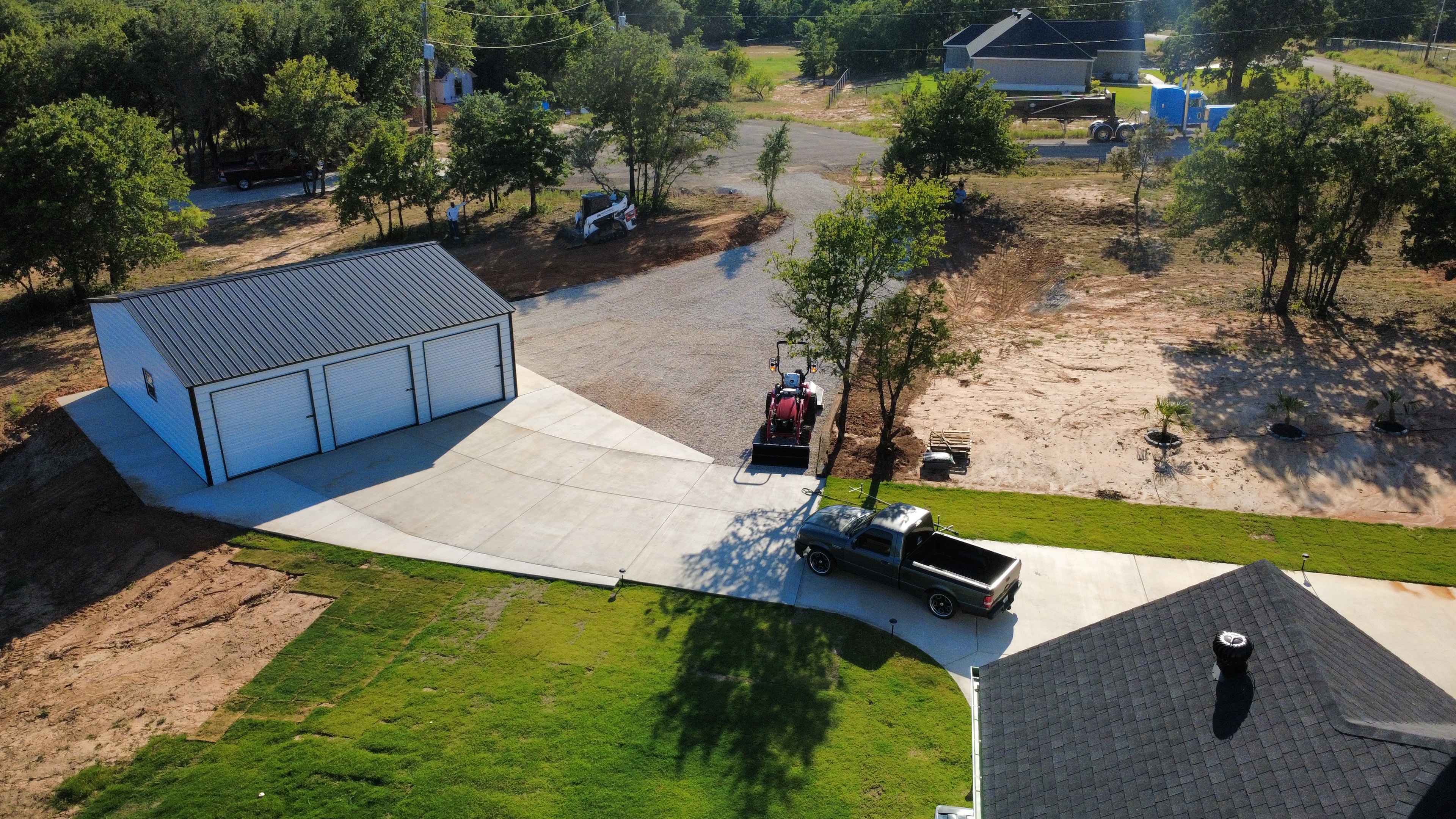 Aerial view of finished concrete driveway leading to metal building