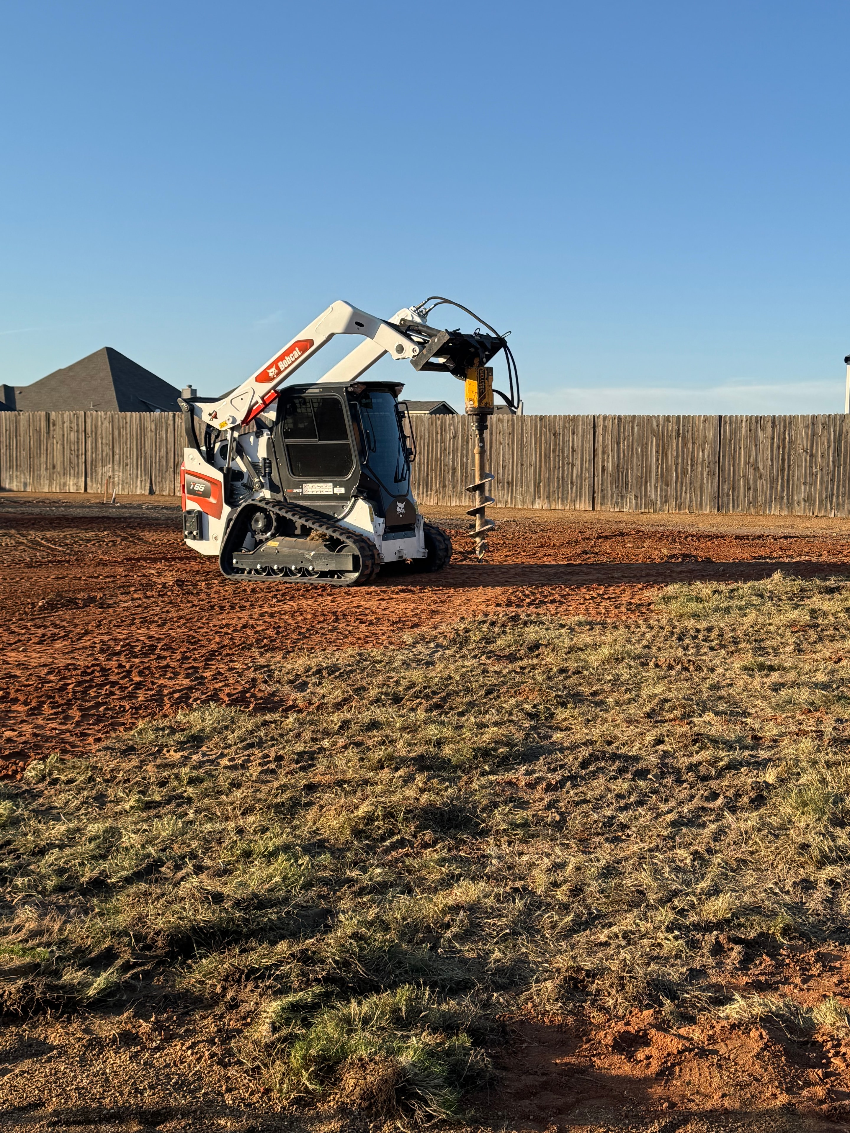 Bobcat with auger attachment on red dirt job site