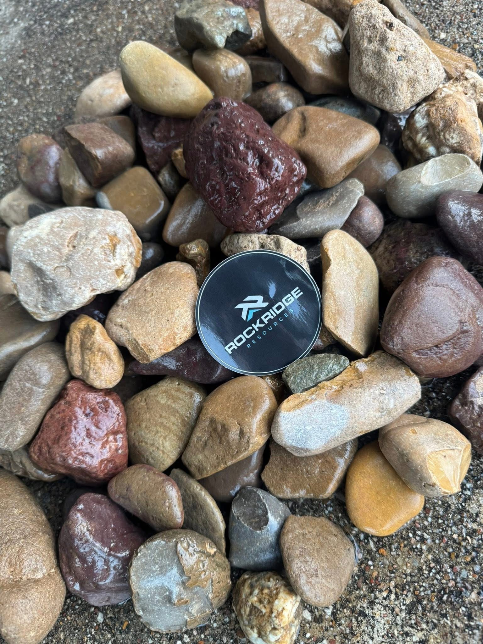 Rockridge Resources logo coin displayed on river rock aggregate